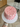 Two-tiered cake with red heart patterns held by a person indoors.